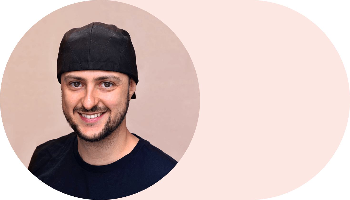 Smiling Andrés Rigo portrait looking at the camera. He is wearing black shirt and a cap