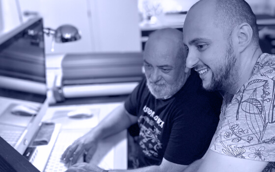 Andrés Rigo interacts with another colleague in front of a computer. Both are looking at the screen and having a talk about design