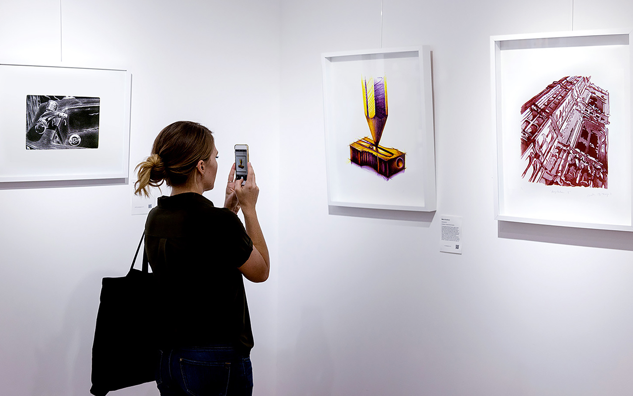 A woman taking a picture of an art exhibit, enjoying the beauty and creativity on display